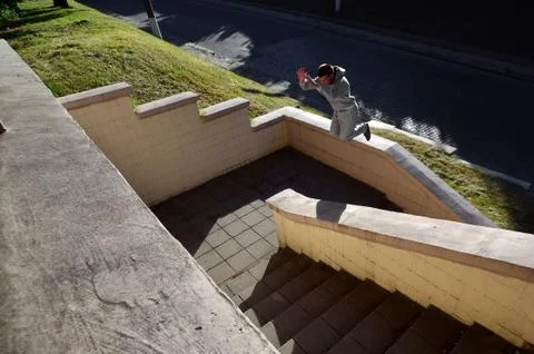 A young guy performs a jump through the space between the concrete parapets.  Stock Photos