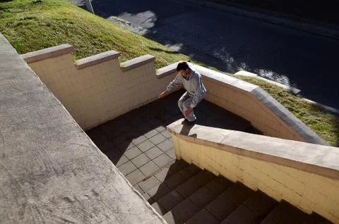 A young guy performs a jump through the space between the concrete parapets.  写真素材