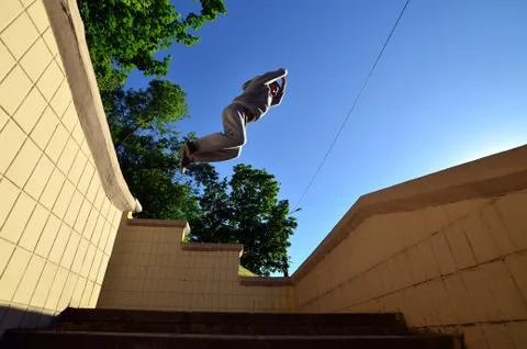 A young guy performs a jump through the space between the concrete parapets.  写真素材