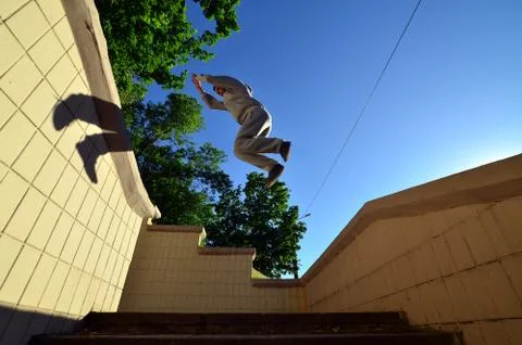 A young guy performs a jump through the space between the concrete parapets.  写真素材