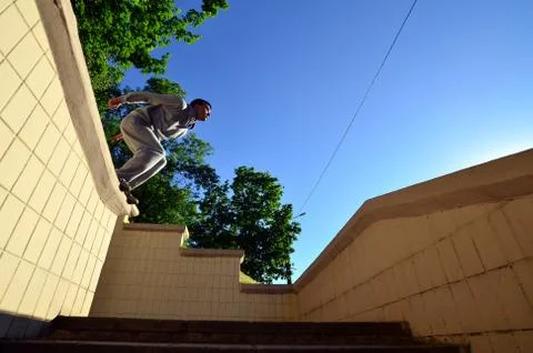A young guy performs a jump through the space between the concrete parapets.  写真素材