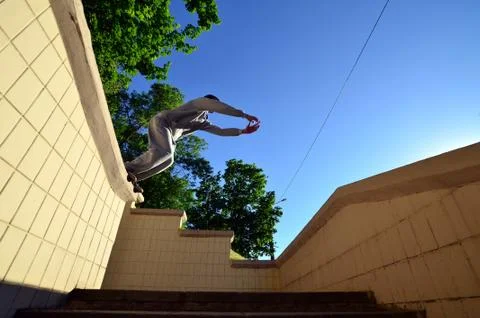 A young guy performs a jump through the space between the concrete parapets.  写真素材