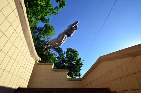 A young guy performs a jump through the space between the concrete parapets.  写真素材