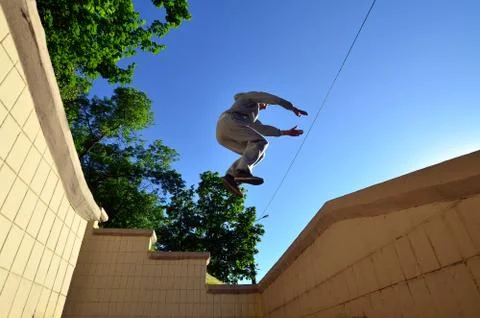 A young guy performs a jump through the space between the concrete parapets.  写真素材