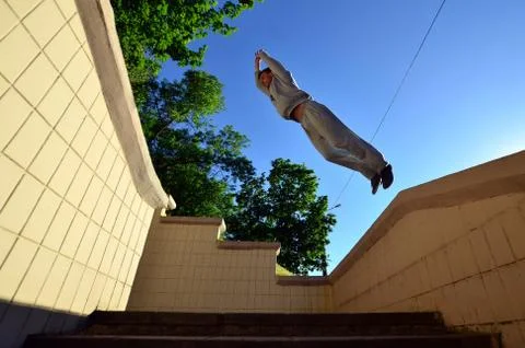 A young guy performs a jump through the space between the concrete parapets.  写真素材