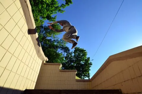 A young guy performs a jump through the space between the concrete parapets.  写真素材