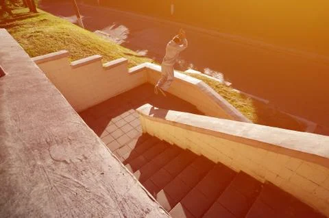 A young guy performs a jump through the space between the concrete parapets.  写真素材