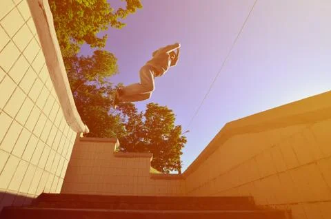 A young guy performs a jump through the space between the concrete parapets.  写真素材