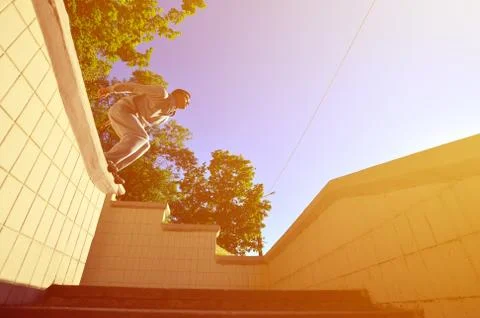 A young guy performs a jump through the space between the concrete parapets.  写真素材