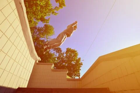 A young guy performs a jump through the space between the concrete parapets.  写真素材