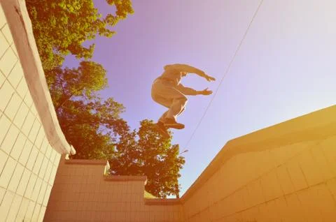 A young guy performs a jump through the space between the concrete parapets.  写真素材