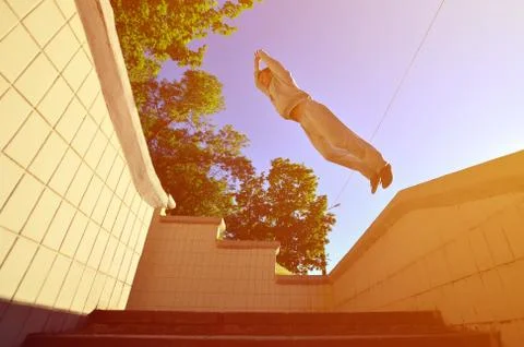 A young guy performs a jump through the space between the concrete parapets.  写真素材