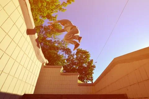 A young guy performs a jump through the space between the concrete parapets.  写真素材