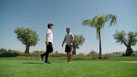 A young guy with a personal trainer squats on one leg for coordination and Stock Footage 171571611