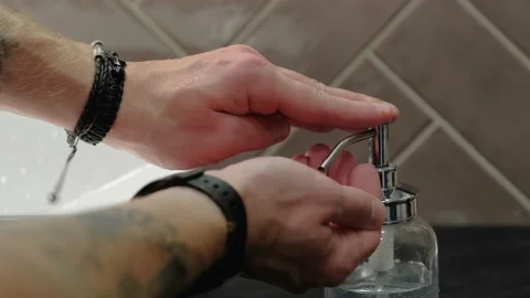 Young guy picks up liquid soap from a bottle and thoroughly lathers his hands Video stock 138999081