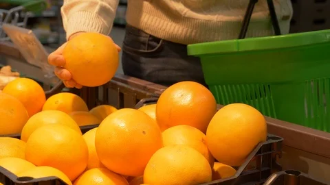 Young guy picks oranges in a supermarket,  Healthy food, fruit, citrus, fresh Stock Footage 103584858