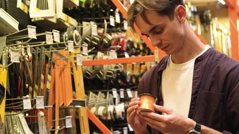 A young guy picks out tools in a hypermarket. Stock Footage 282923572