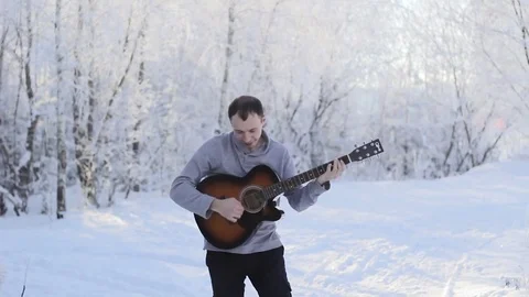 Young guy playing the guitar in the snowy forest Stock Footage 85403891