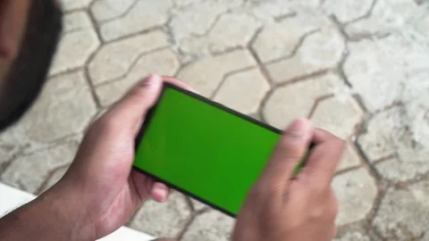 Young guy playing on his phone green screen games enjoying smartphone Stock Footage 127808626