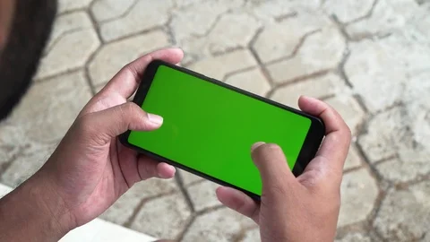 Young guy playing on his phone green screen games enjoying smartphone Video stock 127808766