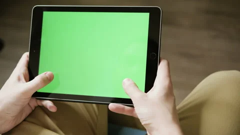 A young guy plays a racing simulator on a tablet. Green screen for quick Video stock 171014697