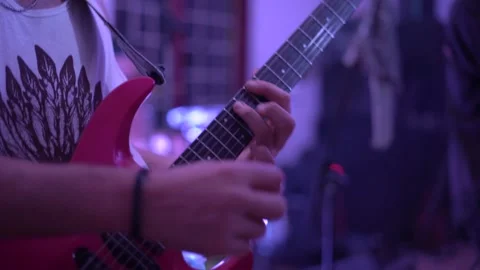 Young guy plays red guitar performing on stage with band Stock Footage 146171295