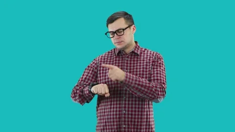 A young guy  points to a wristwatch, taps it with his finger. Video stock 133185140
