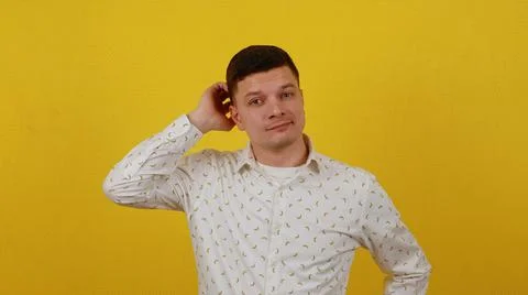 Young guy posing on a yellow background. Thinks, fantasizes, dreams and seeks Stock Photos