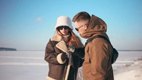 Young guy pours tea from a thermos for his girlfriend. Winer. Video stock 150331151