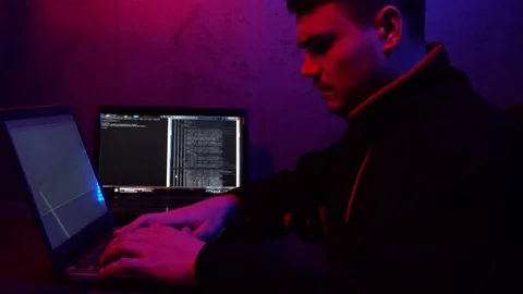 Young guy programmer working at computer.Hacking system, blue red light Stock Footage 124360798