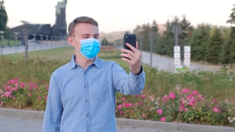 A young guy in a protective mask communicates in video chat on the street Video stock 140735354