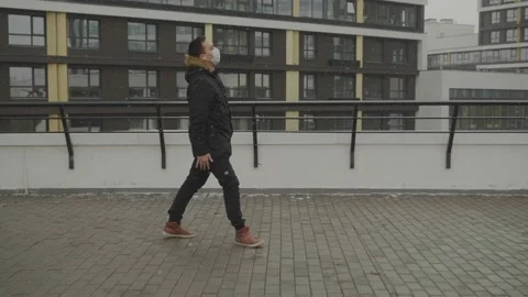 Young guy in a protective mask during a coronavirus walks on the roof and dances 스톡 동영상 134133851