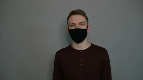 Young guy in a protective mask on a gray background. Protection first Stock Footage 129022175