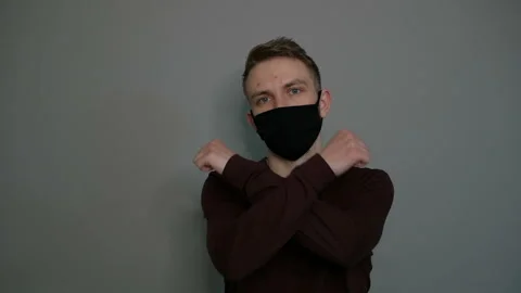 Young guy in a protective mask on a gray background. Shows a stop. Stop Stock Footage 129026369