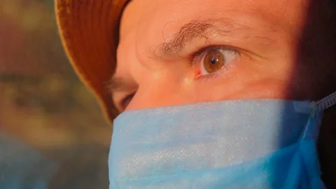 Young guy in a protective mask while traveling by train, bus, car. Sun light on Stock Footage 138573442