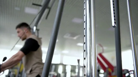 A young guy pumping his chest and biceps on the crossover, in the gym Stock Footage 74799506