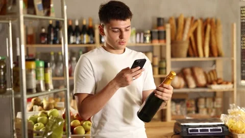 Young guy purchaser scanning with smartphone QR code label of bottle of spark Stock Footage 307146231
