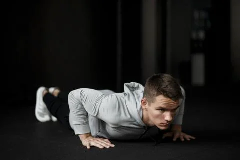 Young guy is push ups in the gym, he is dressed in a sporting uniform Stock Photos