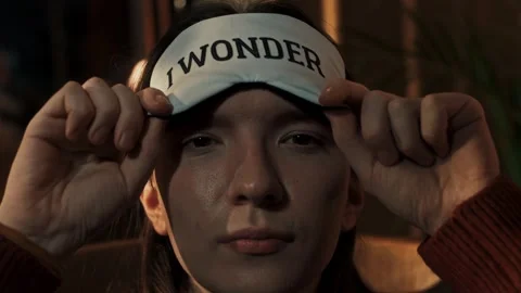 Young guy puts on a mask over his eyes from the light before going to bed Stock Footage 312077734