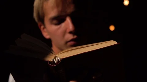 Young guy is reading a book, the focus is on the book Stock Footage 119712045