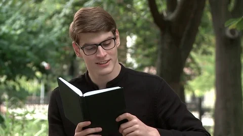 A young guy is reading a book in the park Stock Footage 79527212