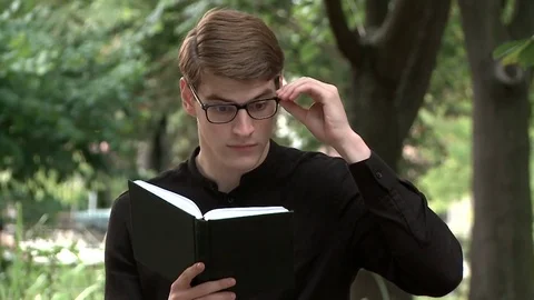 A young guy is reading a book in the park Stock Footage 79527217
