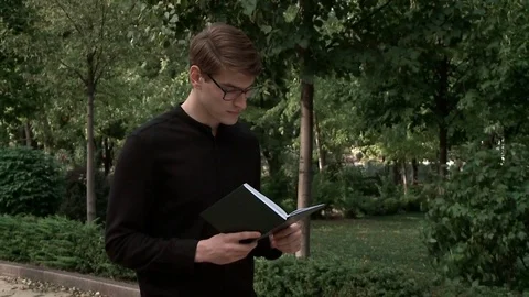 A young guy is reading a book in the park Stock Footage 79527635