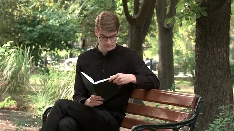 A young guy is reading a book in the park Stock Footage 79527813