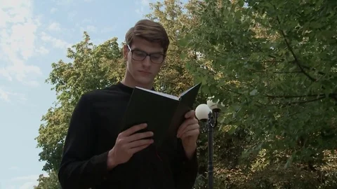 A young guy is reading a book in the park Stock-Footage 79527822
