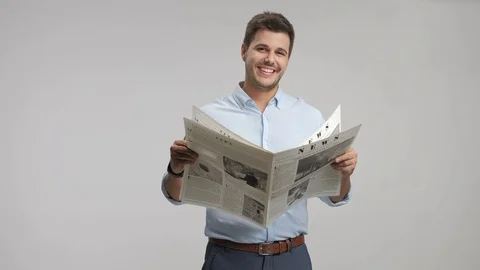 Young guy reading a newspaper and smiling 스톡 동영상 77829474