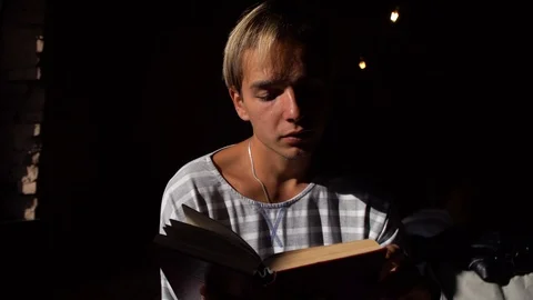 A young guy reads a book and then looks out the window Stock Footage 119712015