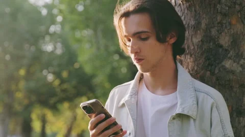 Young  guy received an sms with bad news. Young man in the park picks up hi.. Stock Footage 254656999
