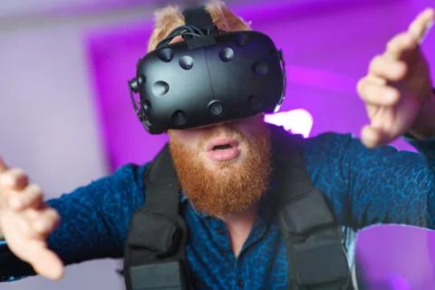A young guy, with a red beard, is playing virtual reality games Stock Photos