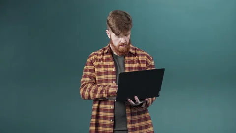 A young guy with red hair and beard reveals serious attitude holding a laptop Stock Footage 170799177
